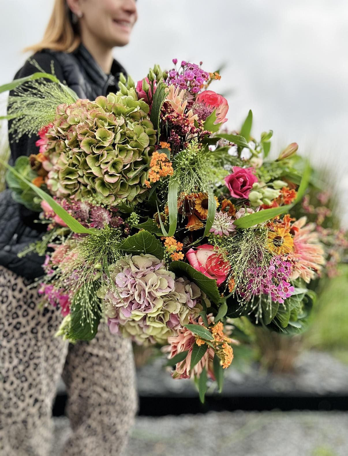 Fleuriste Maison Muscari tenant un grand bouquet aux couleurs automnales